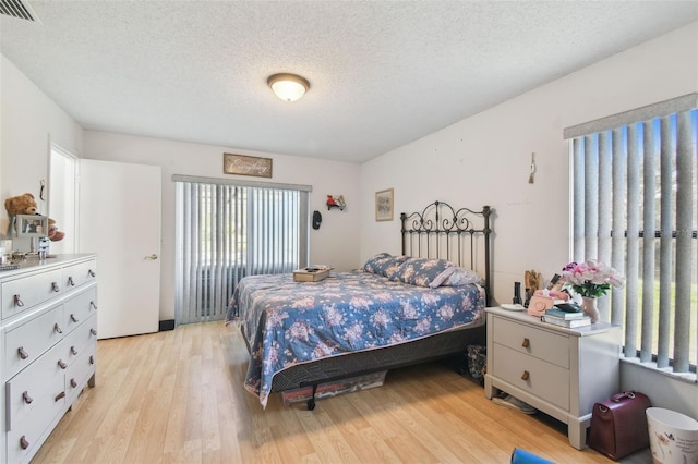 bedroom featuring light hardwood / wood-style floors and a textured ceiling