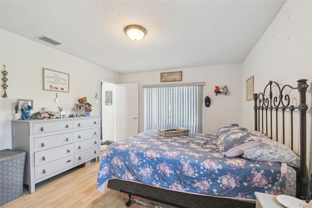 bedroom featuring light hardwood / wood-style flooring and a textured ceiling