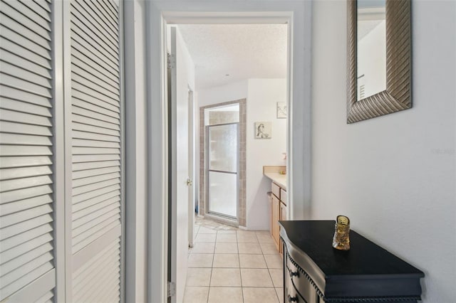 corridor with light tile patterned floors and a textured ceiling