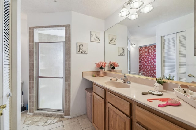 bathroom with tile patterned flooring, vanity, an enclosed shower, and a textured ceiling