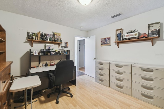 home office featuring a textured ceiling and light hardwood / wood-style floors