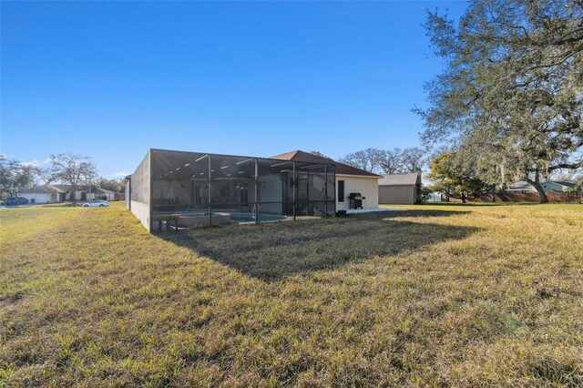 rear view of house with glass enclosure and a lawn