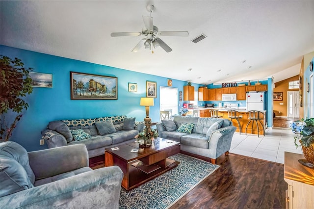 living room with vaulted ceiling, ceiling fan, and light wood-type flooring