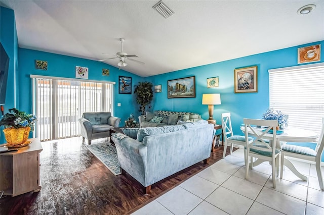 living room with vaulted ceiling, ceiling fan, and light wood-type flooring