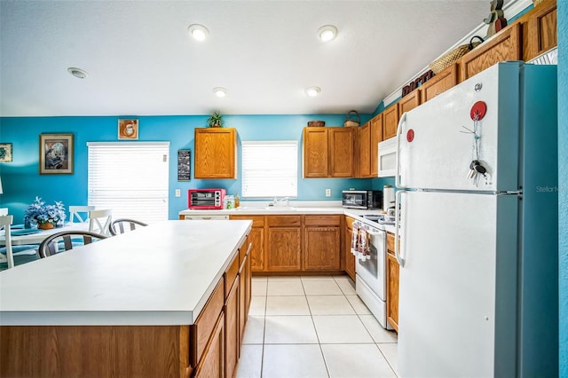 kitchen featuring sink, white appliances, a kitchen island, and light tile patterned flooring