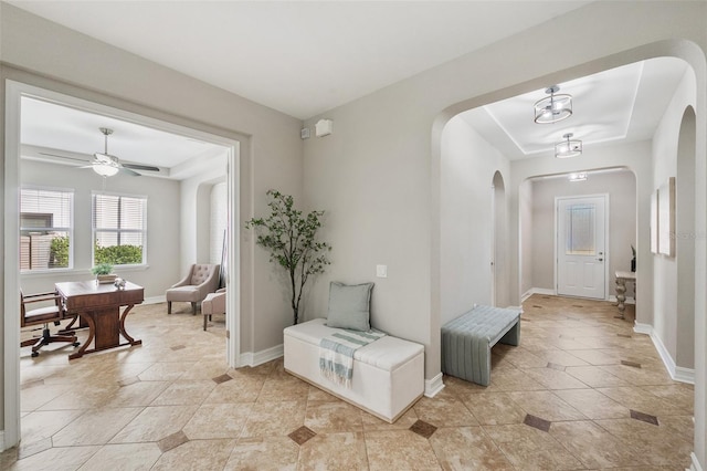 foyer entrance featuring a tray ceiling, ceiling fan, and light tile patterned flooring