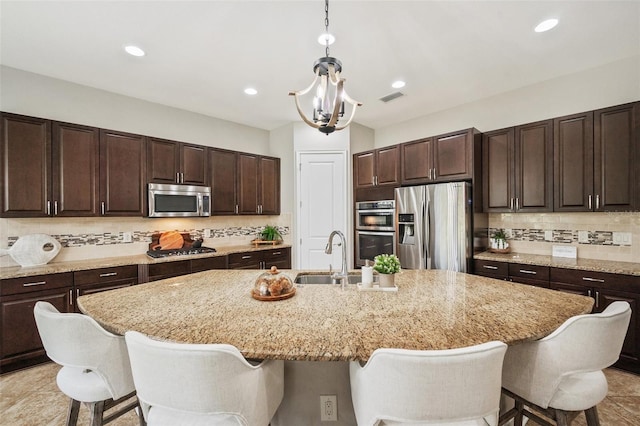 kitchen featuring a kitchen island with sink, sink, dark brown cabinetry, and appliances with stainless steel finishes