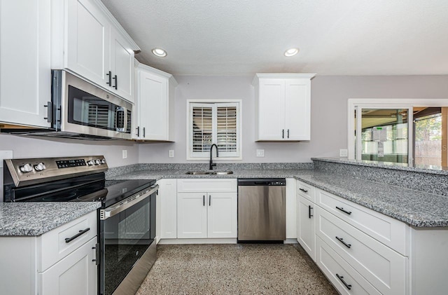 kitchen featuring sink, white cabinetry, a textured ceiling, stainless steel appliances, and light stone countertops