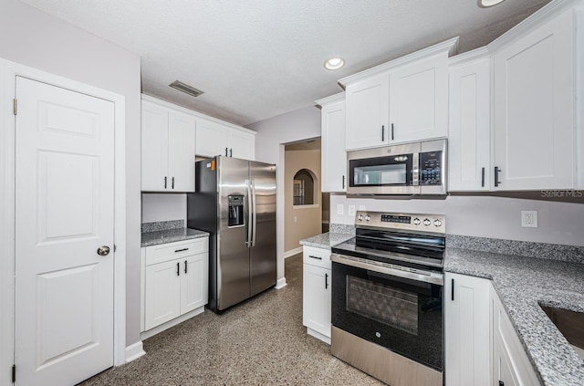 kitchen featuring stainless steel appliances, white cabinetry, light stone countertops, and a textured ceiling