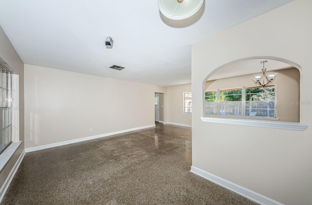 unfurnished room featuring a chandelier