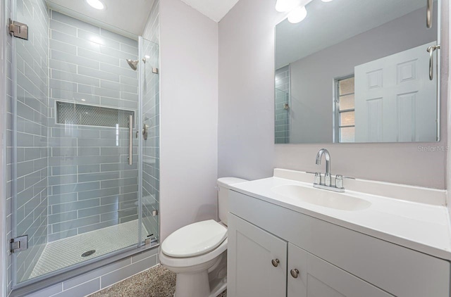 bathroom with vanity, a shower with shower door, and toilet