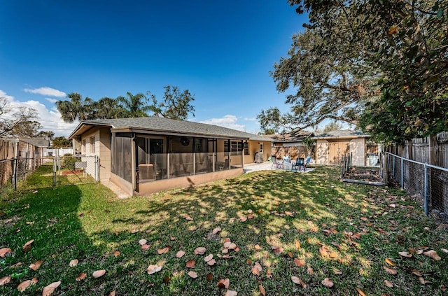 back of property with a lawn, a sunroom, and a patio area