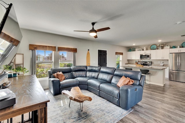 living room with ceiling fan, light hardwood / wood-style flooring, and a textured ceiling