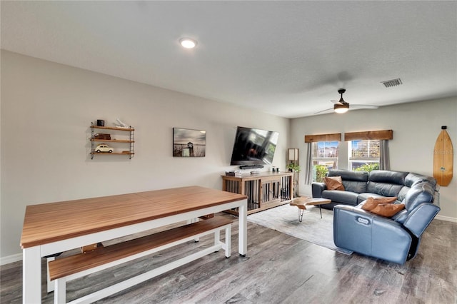 living room with hardwood / wood-style flooring, ceiling fan, and a textured ceiling