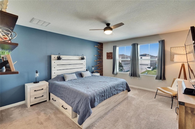 bedroom with ceiling fan, light colored carpet, and a textured ceiling