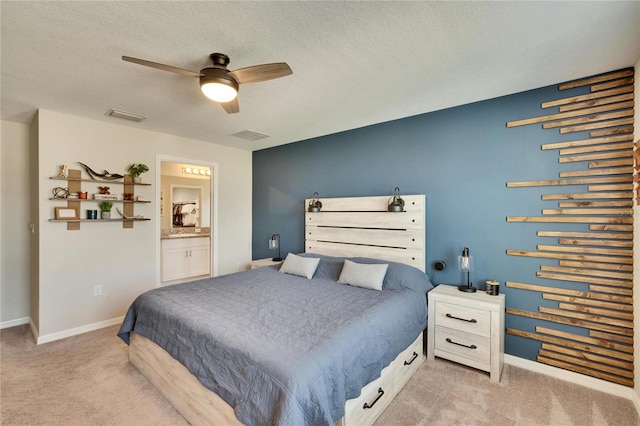 bedroom featuring ceiling fan, light colored carpet, connected bathroom, and a textured ceiling