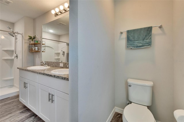 bathroom featuring toilet, wood-type flooring, vanity, and walk in shower