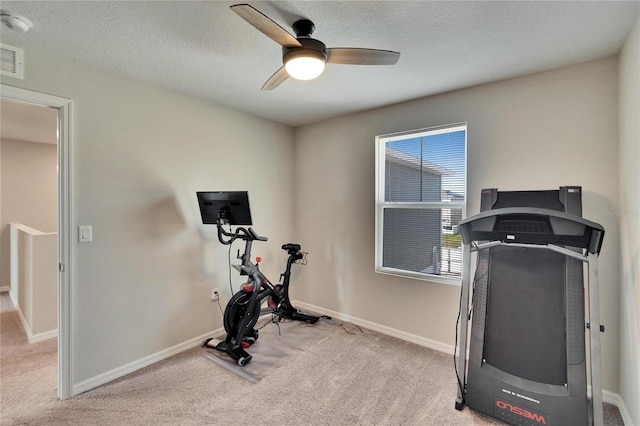 exercise area with ceiling fan, light carpet, and a textured ceiling