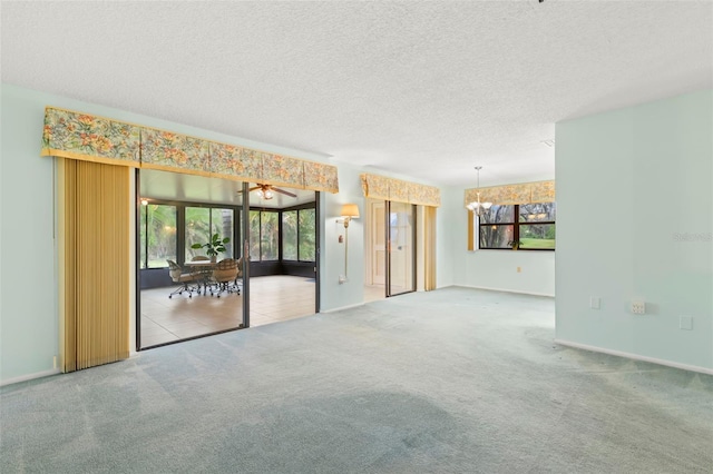 spare room with carpet floors, an inviting chandelier, baseboards, and a textured ceiling