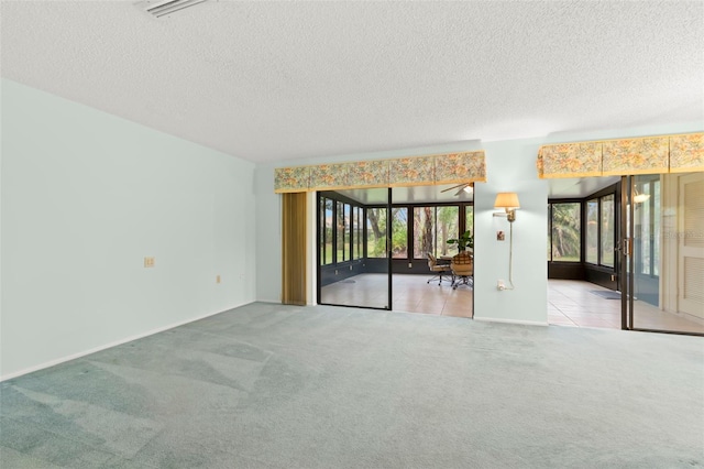 carpeted spare room featuring visible vents, a textured ceiling, and tile patterned floors