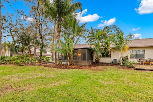 rear view of house featuring a deck, a yard, cooling unit, and a sunroom