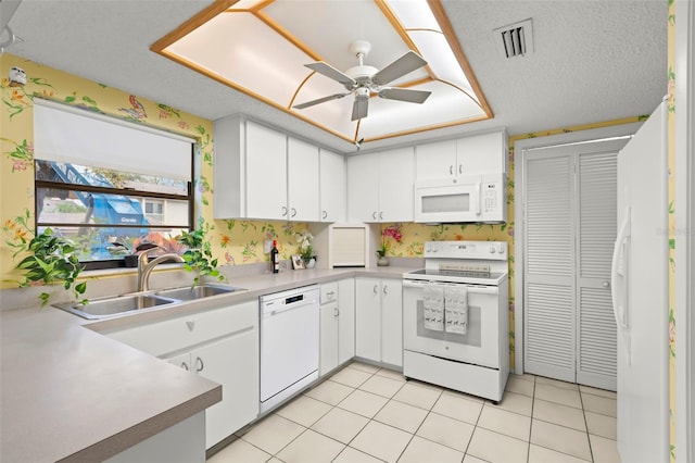 kitchen featuring light tile patterned floors, white appliances, a sink, visible vents, and white cabinetry