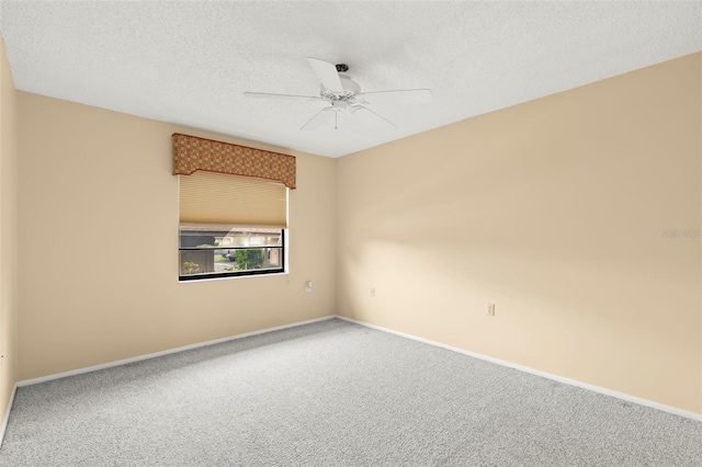 carpeted spare room featuring a ceiling fan, a textured ceiling, and baseboards