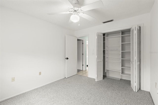 unfurnished bedroom with a textured ceiling, ceiling fan, visible vents, a closet, and carpet