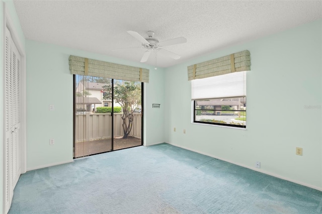 carpeted empty room with ceiling fan, a textured ceiling, and baseboards