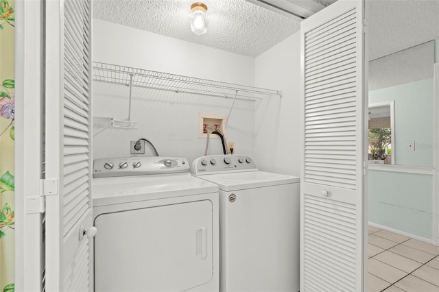 laundry room featuring washer and dryer, laundry area, a textured ceiling, and light tile patterned floors