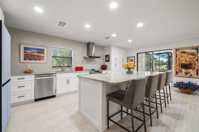 kitchen with a sink, visible vents, stainless steel dishwasher, a center island, and wall chimney exhaust hood