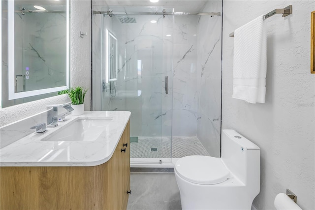 bathroom with a textured wall, a marble finish shower, and vanity