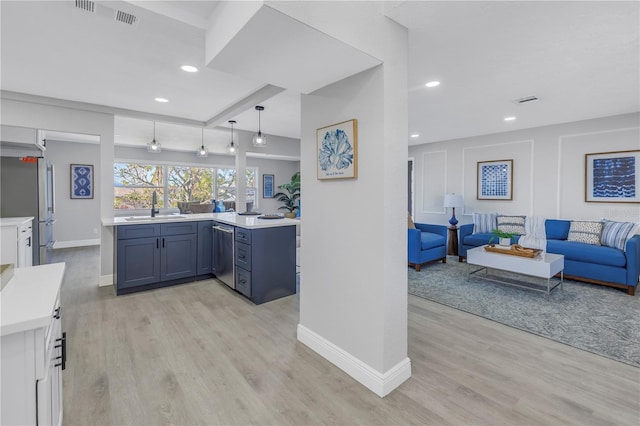 kitchen with stainless steel appliances, light countertops, open floor plan, a sink, and a peninsula