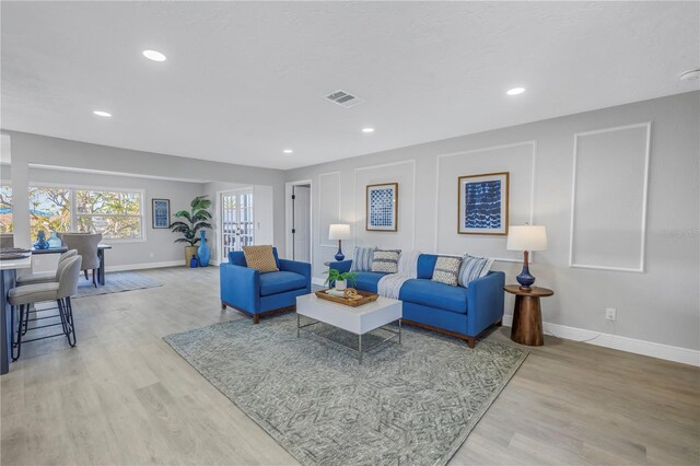 living room with baseboards, recessed lighting, visible vents, and light wood-style floors