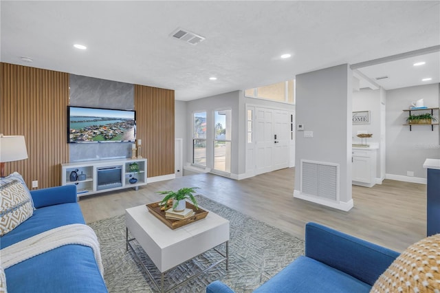 living area featuring baseboards, light wood-type flooring, visible vents, and recessed lighting