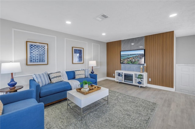 living area featuring baseboards, visible vents, wood finished floors, a textured ceiling, and recessed lighting