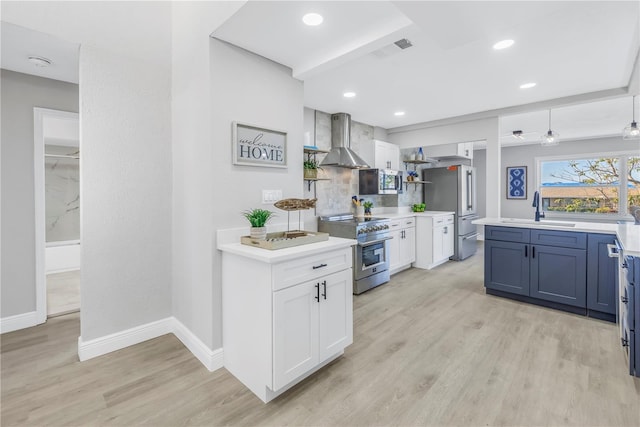 kitchen with white cabinetry, wall chimney exhaust hood, appliances with stainless steel finishes, and light countertops