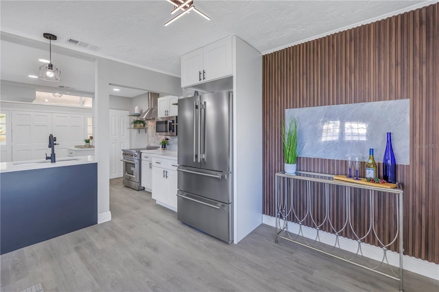 kitchen with high end appliances, light countertops, visible vents, light wood-style flooring, and white cabinets