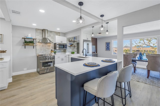 kitchen with white cabinetry, light countertops, wall chimney range hood, open shelves, and high end appliances