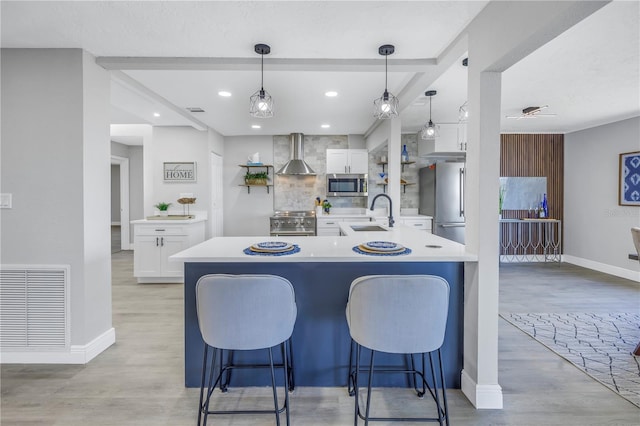 kitchen featuring light countertops, visible vents, appliances with stainless steel finishes, white cabinets, and wall chimney range hood