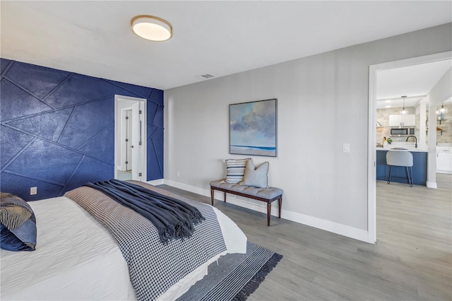 bedroom featuring visible vents, baseboards, and wood finished floors