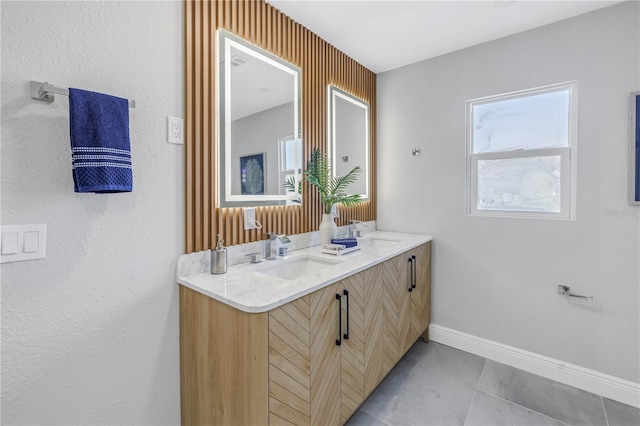 full bath with tile patterned flooring, a sink, baseboards, and double vanity