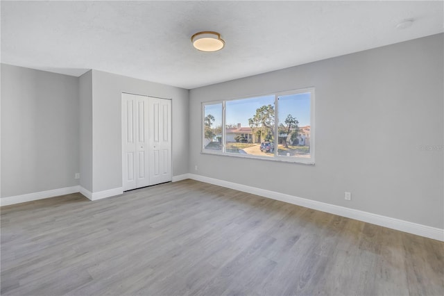 unfurnished bedroom with light wood-style flooring, a textured ceiling, baseboards, and a closet