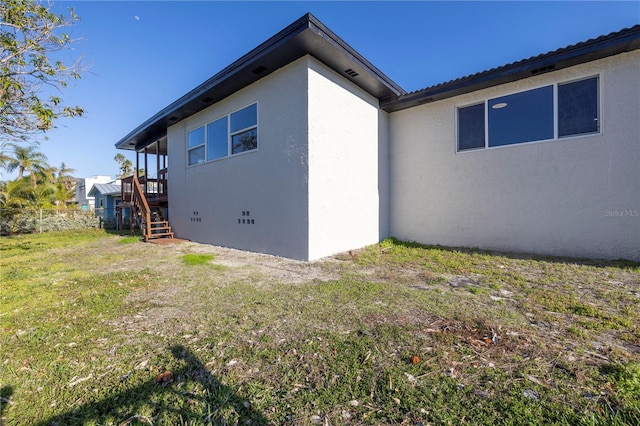 view of home's exterior with stairs, a yard, crawl space, and stucco siding