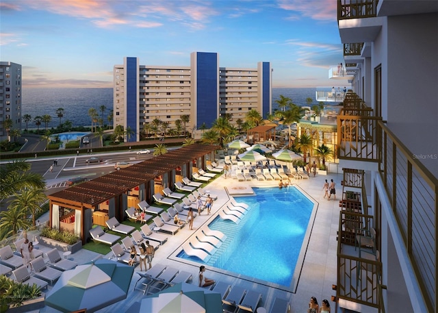 pool at dusk featuring a patio area and a pergola