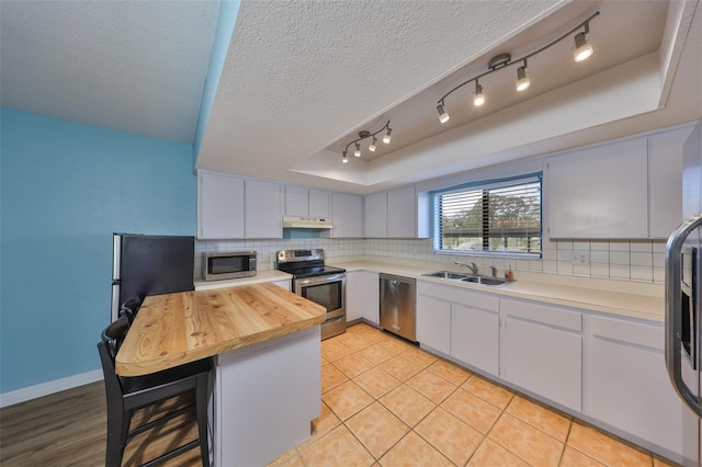 14505 Catalina Cir, Seminole, FL 33776 - kitchen with sink, stainless steel appliances, tasteful backsplash, a kitchen bar, and a raised ceiling