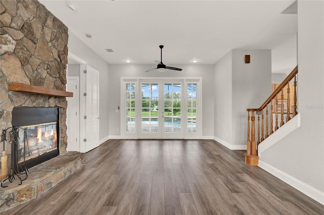 unfurnished living room with a fireplace, wood finished floors, baseboards, french doors, and stairway