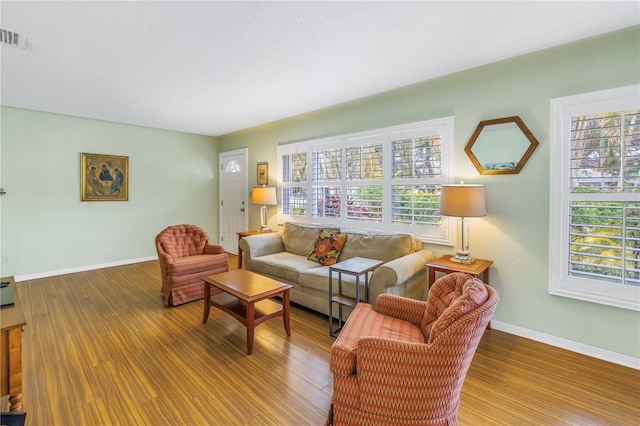 living area featuring visible vents, a textured ceiling, baseboards, and wood finished floors