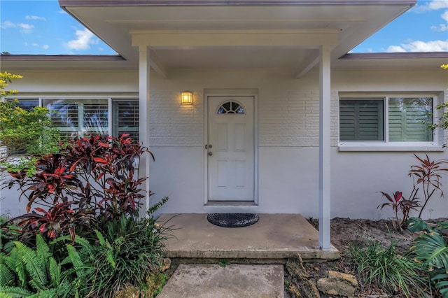 property entrance featuring brick siding and stucco siding