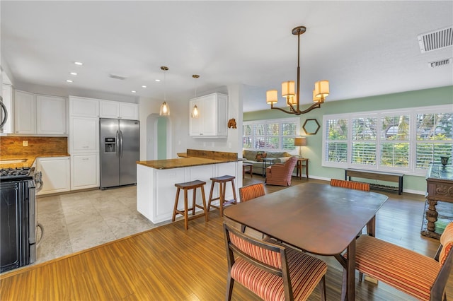 dining area with arched walkways, a notable chandelier, light wood finished floors, recessed lighting, and visible vents